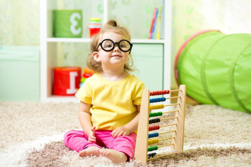 女孩戴眼镜玩珠算玩具