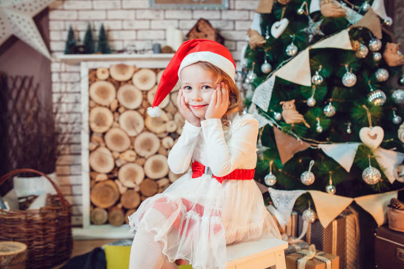坐在圣诞树前微笑的小女孩