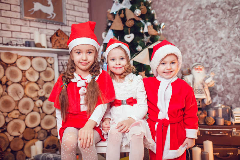 室内装扮成圣诞老人的三个小孩子