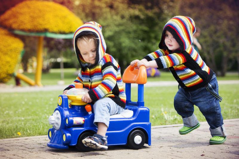 在户外草地上玩玩具车的男孩们