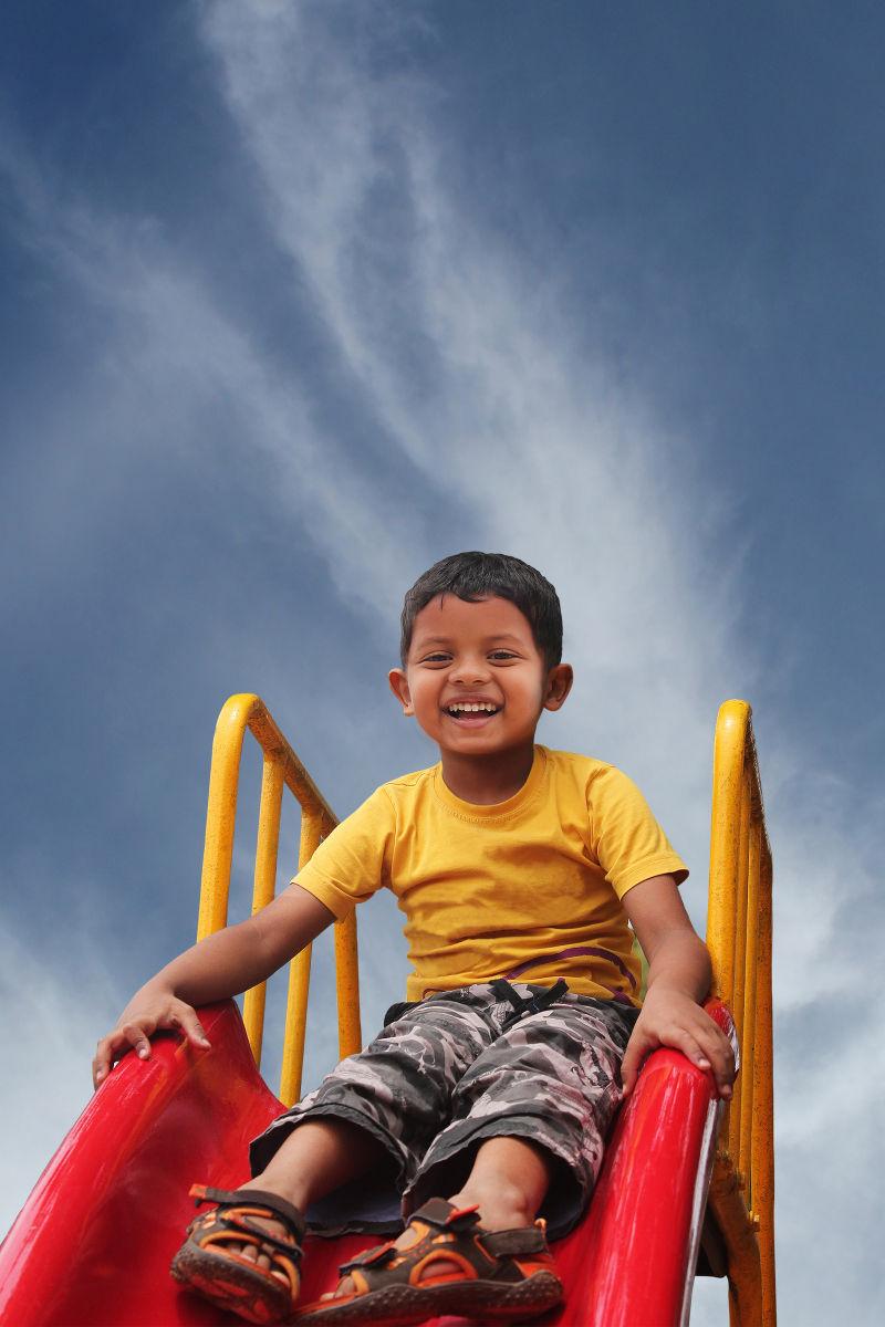 快乐微笑的印度孩子在玩滑梯