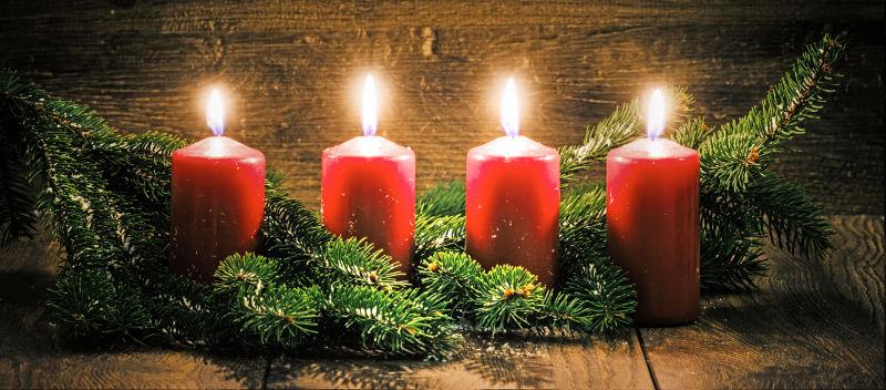 在圣诞的背景下的四个燃烧的蜡烛装饰