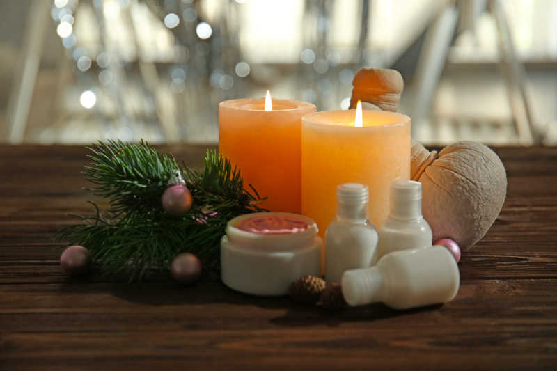 有小彩灯的背景下木桌上的蜡烛护肤品和圣诞节装饰