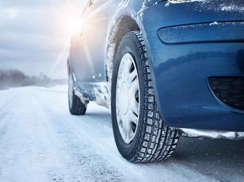 阳光下冬天路上的雪天的汽车轮胎特写