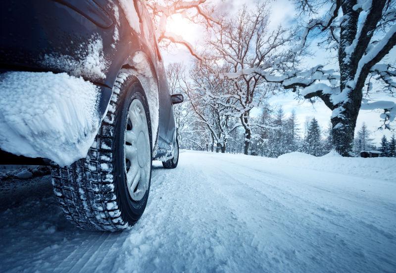 阳光下冬天有雪的公路上的汽车轮胎