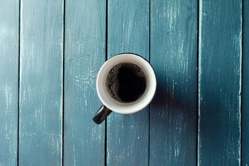蔚蓝色木桌上的白色咖啡杯