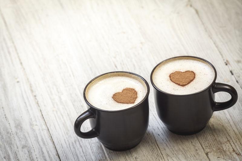 木桌上两杯心形状的咖啡