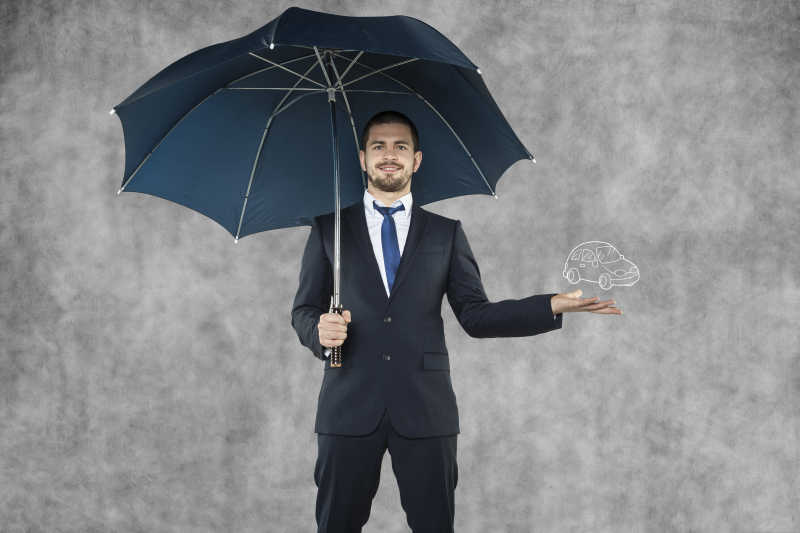 撑着雨伞的男人手里的汽车保险概念