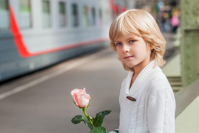 男孩拿着一朵粉玫瑰
