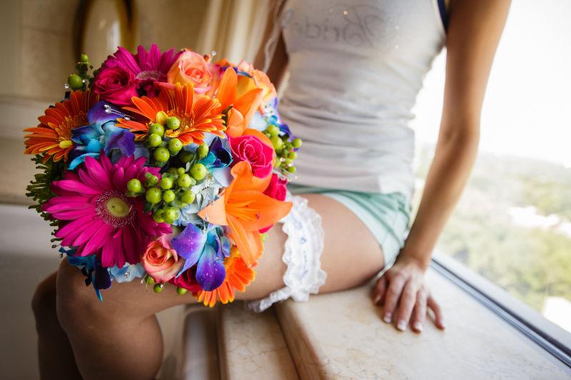 坐在窗台上休息的新娘带着五颜六色的花束