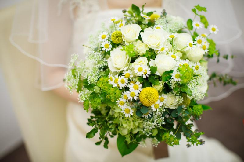 穿着白色婚纱的美丽新娘手持捧花
