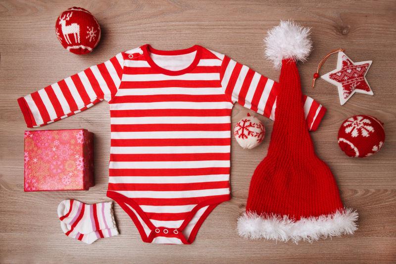 木制背景下带圣诞饰品的圣诞婴儿服装