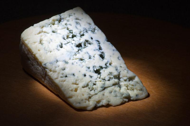 黑色背景下木板上的蓝色奶酪