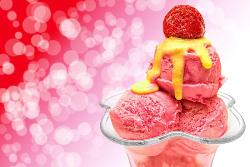 粉色和红色背景下的玻璃容器里的草莓味道的冰激凌球