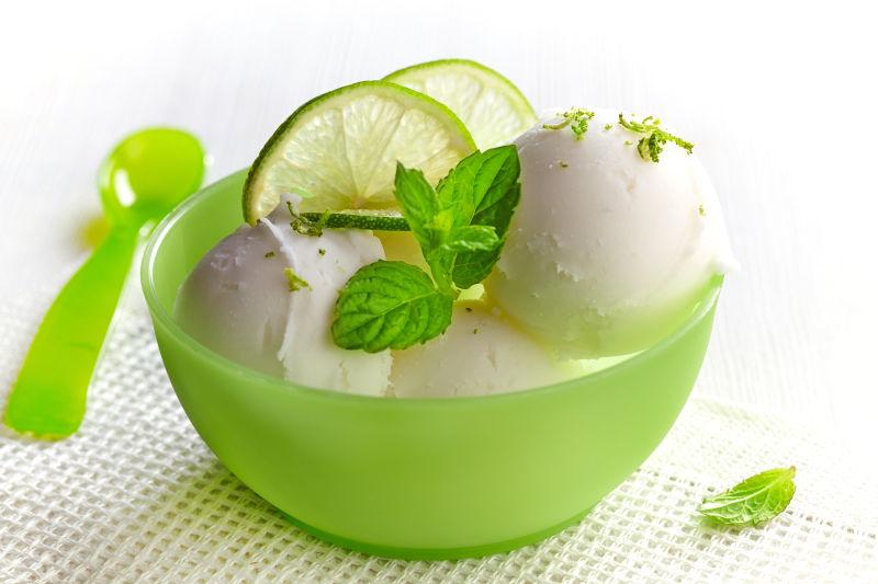 白色背景上的绿色碗里的白色薄荷味冰激凌球