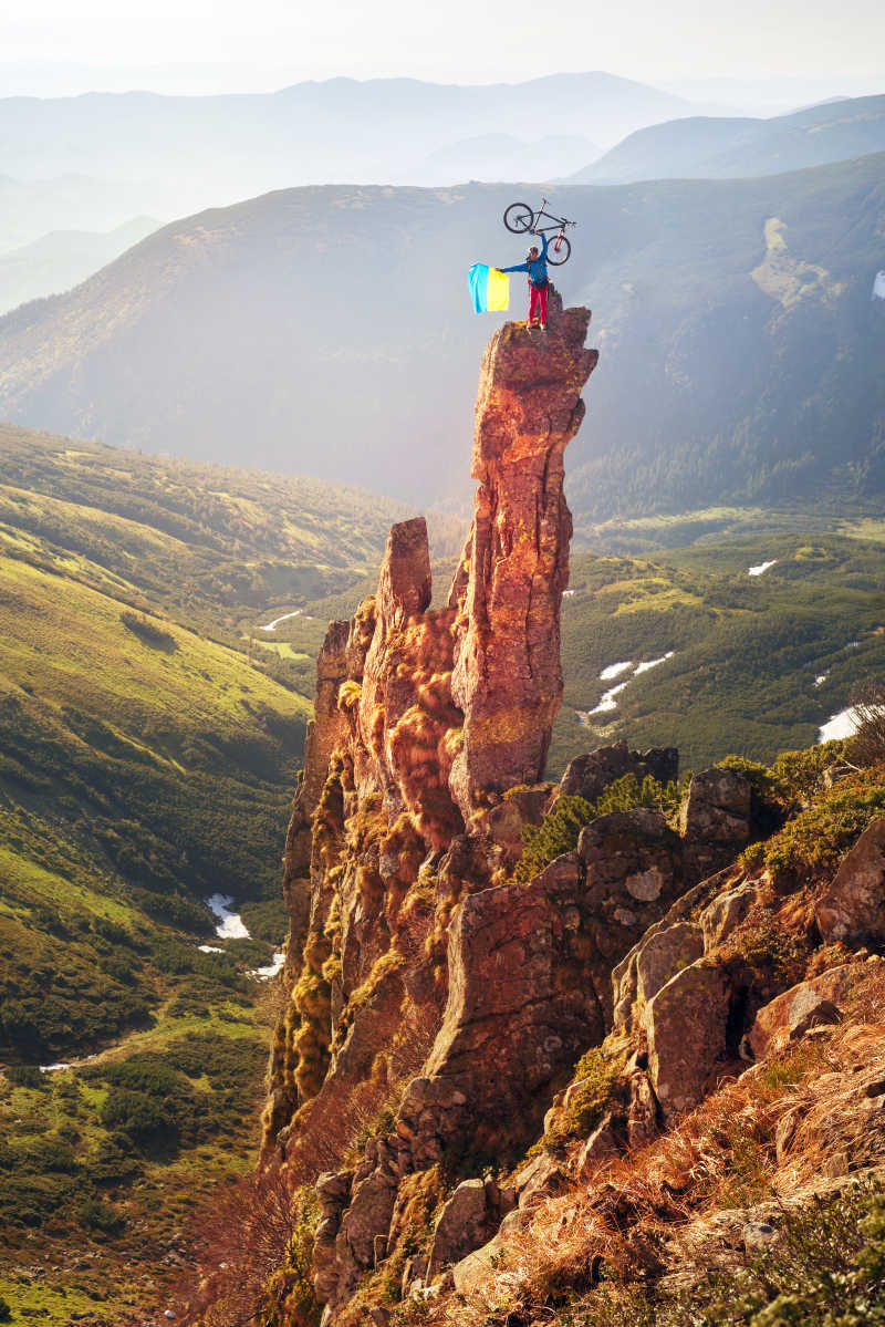 山峰上举着自行车的极限运动员