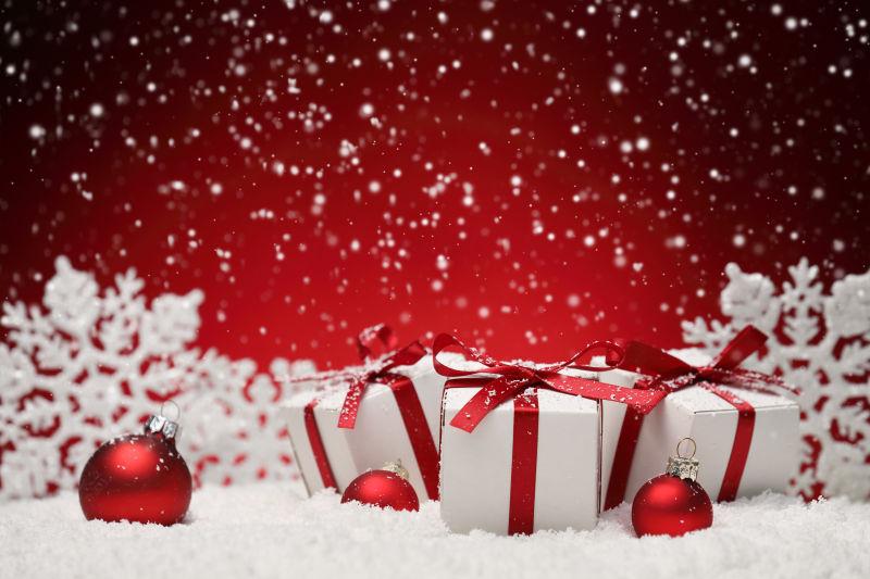 红色背景雪花上的圣诞节礼物和装饰品