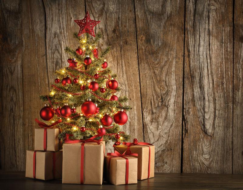 木制背景下用小红球装饰的圣诞树和礼物