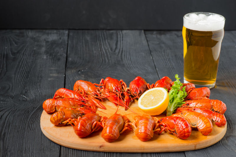 一杯啤酒和木板上煮熟的红色小龙虾