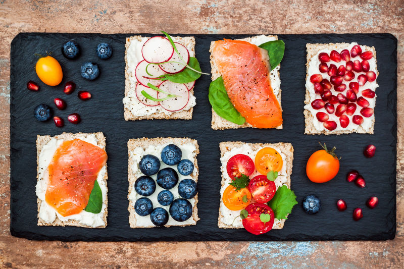 放在黑色木板上的三明治搭配各种不同的美食与水果